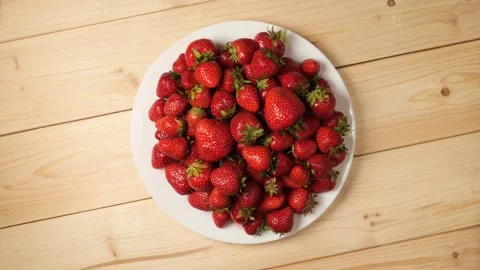 Rotating plate of fresh red strawberries on wood table Видео 340526383