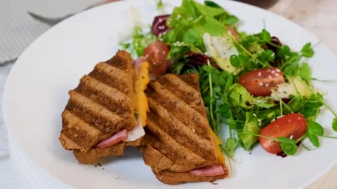 Rotating plate with grilled cheese and ham sandwich and fresh salad Vídeos de archivo 332893200