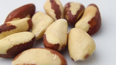 Rotating of raw brasilian nuts on white background. Side view. Stock Footage 136050344