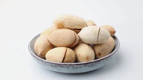 Rotating of raw pecan nuts in ceramic plate on white background. Side view. Stock Footage 136050548