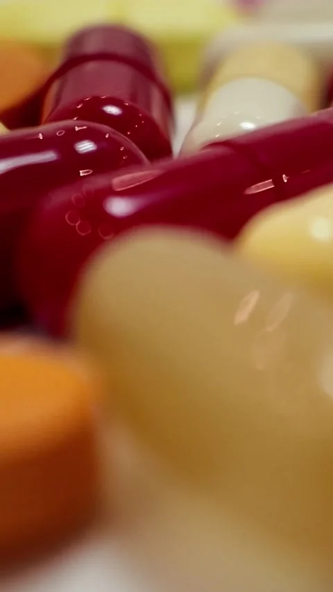Rotating red and beige capsules macro shot - Vertical Version Stock Footage 345164451