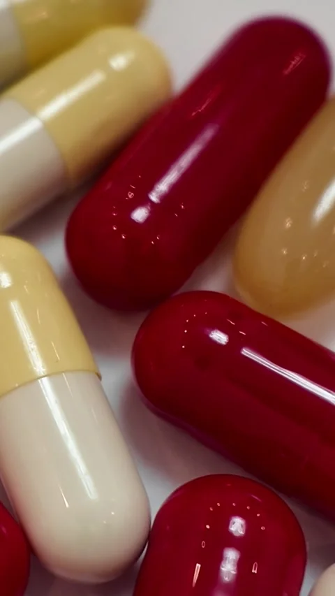 Rotating red and white capsules and pills macro close up - Vertical Version Stock Footage 345164398