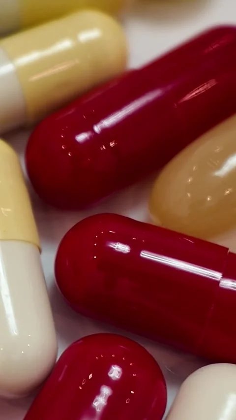 Rotating red and white capsules and pills macro close up - Vertical Version Stock Footage 345164417