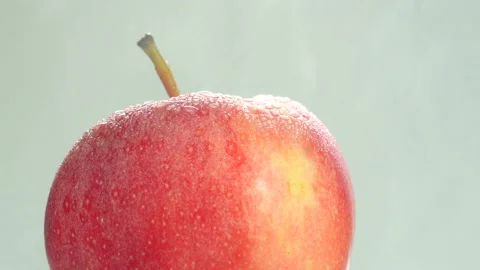Rotating red apple, covered in raindrops and rain is falling on top Stock Footage 234899889