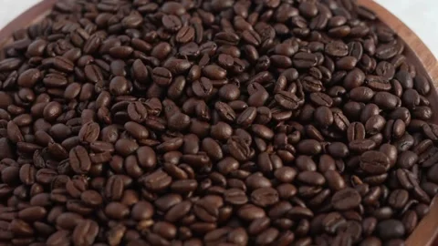 Rotating roasted coffee beans on wooden board close up in 4K Stock Footage 330119829