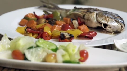 Rotating roasted sea bream fish with with vegetables, sauce, and fresh salad Stock Footage 122233276