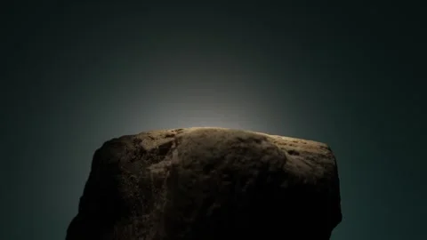 Rotating rock podium highlighted in soft spotlight on dark background Stock Footage 312517252