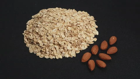 Rotating Rolled Oats and Raw Almonds on Black Background. Stock Footage 333050840
