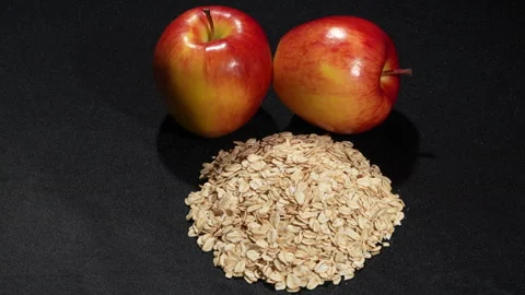 Rotating Rolled Oats with Two Fresh Red Apples on Black Background. Stock-Footage 333091459