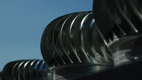 Rotating rooftop turbine ventilators against clear blue sky Stock Footage 346550554