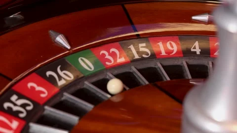 Rotating roulette wheel with central spindle and ball positioned in pocket 0 Stock Footage 336406199