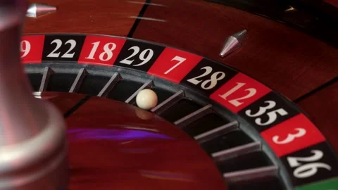 Rotating roulette wheel with central spindle and ball in pocket 7 Stock Footage 336406374