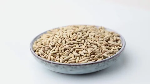 Rotating of rye grains  in ceramic plate on white background. Side view. Stock Footage 136050648