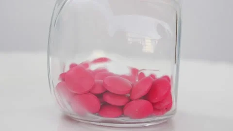 Rotating shot of pink tablets in a transparent glass bottle Видео 147700122