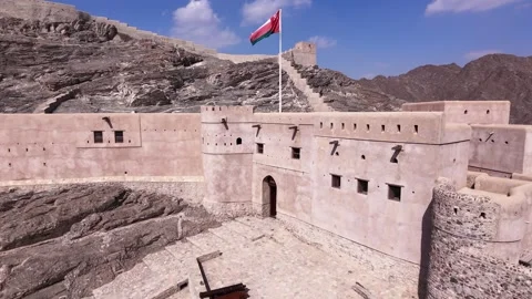 A rotating side-tracking shot of Samail Fort with the Omani flag waving Stock Footage 338238495