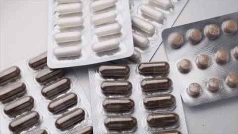 Rotating silver blister pack containing white and brown capsules Stock Footage 277277363