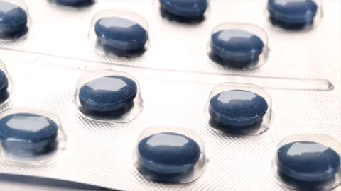 Rotating silver blister pack containing blue pharmaceutical capsules Stock Footage 279748971