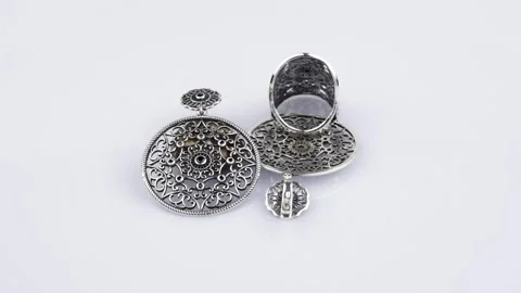 Rotating silver knotted ring and earring with reflection on black background. Stock Footage 291171277