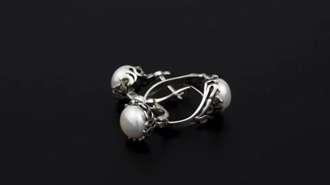 Rotating silver knotted ring and earring with reflection on black background. Stock Footage 291171306