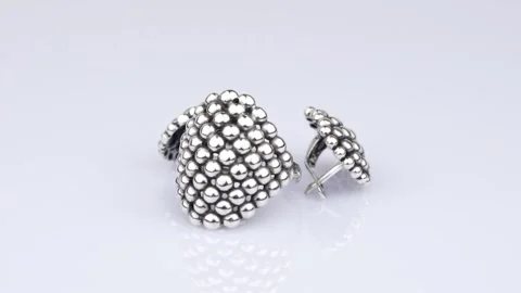 Rotating silver knotted ring and earring with reflection on white background. Stock Footage 291171309