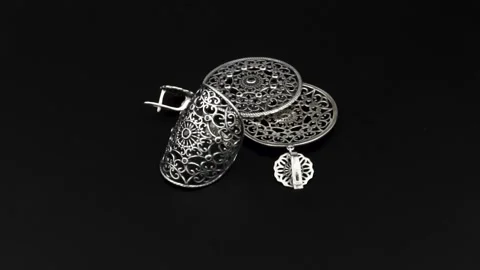 Rotating silver knotted ring and earring with reflection on black background. Stock Footage 291171349