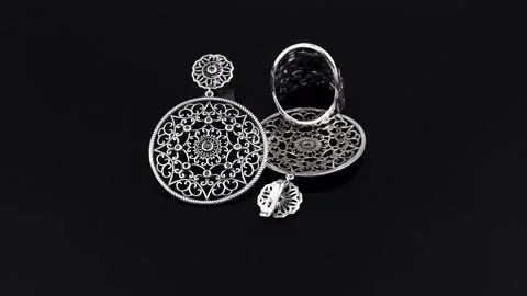 Rotating silver knotted ring and earring with reflection on black background. Stock Footage 291171408