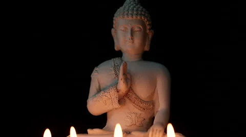 Rotating sitting Buddha statue candle light against black background (loop) Stock Footage 65489478