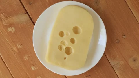 Rotating slice of swiss cheese on a plate Stock Footage 340159390