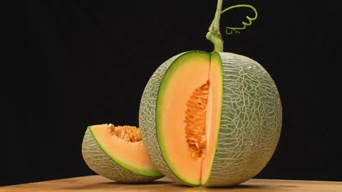 Rotating Sliced Green Netted Melon Orange Flesh On Black Background 4K Stock Footage 323020591