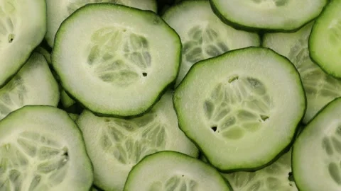 Rotating slides of fresh cucumber in close-up. Green cucumber slices moving in a Stock Footage 304682640