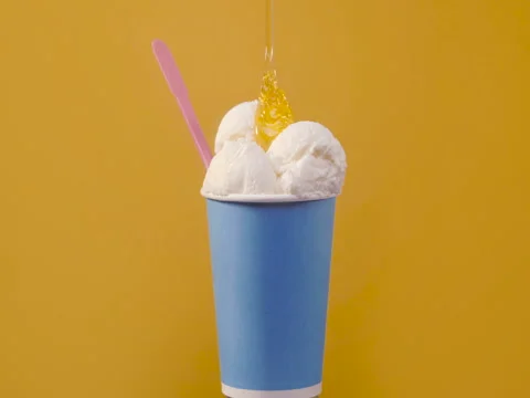 Rotating soft vanilla ice cream in blue paper cup with sweet topping Stock Footage 82878268