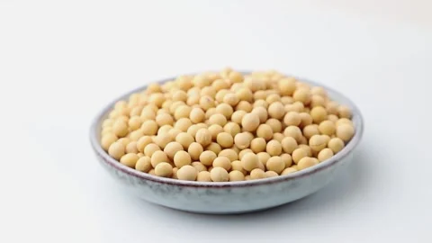 Rotating of soy seeds in ceramic plate on white background. Side view. Stock Footage 136050688