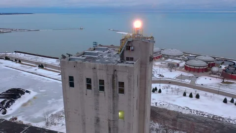 Rotating spotlight on high tower by lake, aerial flyby view. Video stock 124371371