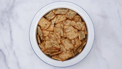 Rotating Square Cracker Biscuit With Vegetable Flavored And Crumbs In White Plat Vídeos de archivo 164315767