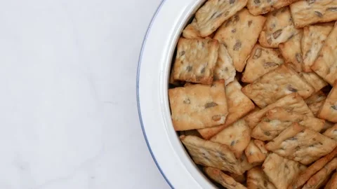 Rotating Square Cracker Biscuit With Vegetable Flavored And Crumbs In White Plat Vídeos de archivo 164315942