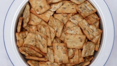 Rotating Square Cracker Biscuit With Vegetable Flavored And Crumbs In White Plat Vídeos de archivo 164315944