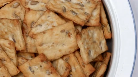 Rotating Square Cracker Biscuit With Vegetable Flavored And Crumbs In White Plat Vídeos de archivo 164315959