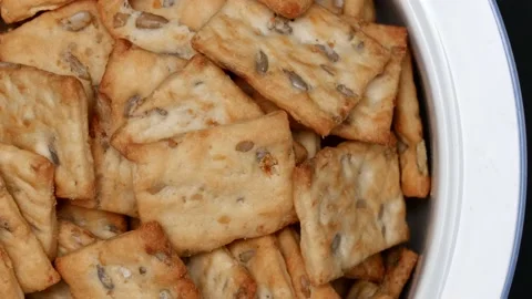 Rotating Square Cracker Biscuit With Vegetable Flavored And Crumbs In White Plat Vídeos de archivo 164315987