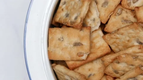 Rotating Square Cracker Biscuit With Vegetable Flavored And Crumbs In White Plat Vídeos de archivo 164316035