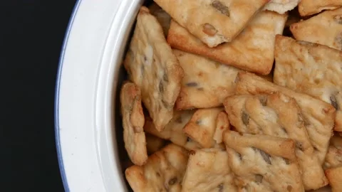Rotating Square Cracker Biscuit With Vegetable Flavored And Crumbs In Black Plat Vídeos de archivo 164316044