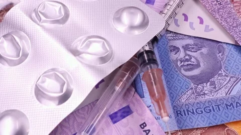 Rotating syringe and used empty pill blisters over Malaysian ringgit banknotes. Stock Footage 297152074