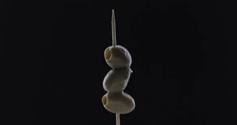 Rotating toothpick with olive on black background Stock Footage 145019947