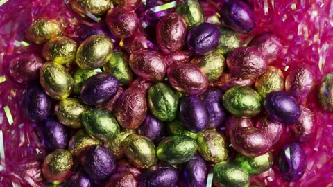 Rotating top down view of chocolate eggs in tinsel Video stock 327910254