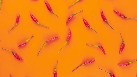 Rotating top view of red peppers over orange background. High contrast backdr Stock Footage 195987244