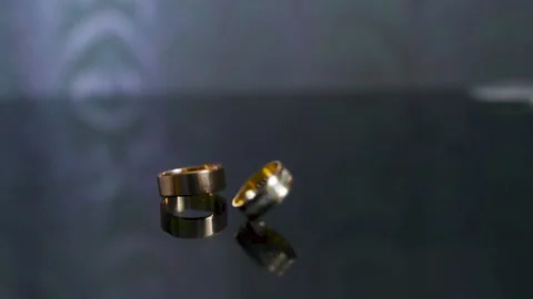 Rotating two wedding rings. Rings rotates in slow motion on the mirror table Stock Footage 202282340