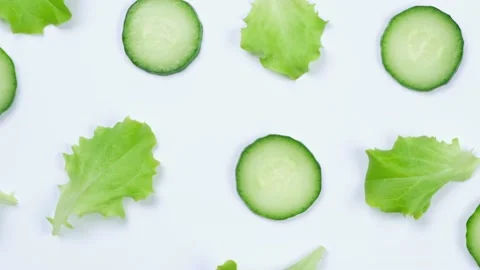 Rotating vegetable background of lettuce leaves, cucumber slices, on a white Stock Footage 196935139