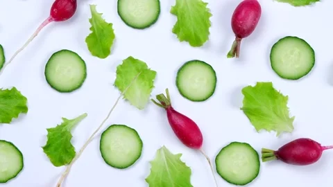 Rotating vegetable background of lettuce leaves, cucumber slices, radishes on a Stock Footage 198133696