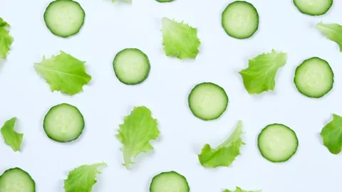 Rotating vegetable background of lettuce leaves, cucumber slices, on a white Stock Footage 198571948