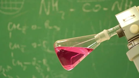 Rotating vessel with red liquid in  the green chalkboard background close-up. Stock-Footage 53543153