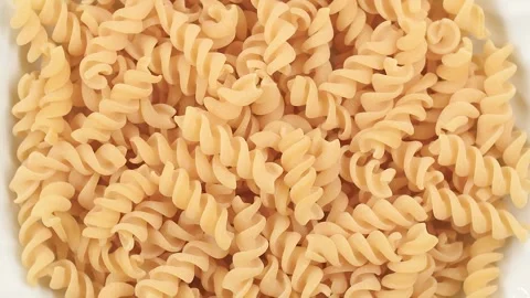 Rotating video close-up of uncooked Fusilli pasta with spiral shapes and smooth Stock Footage 342188603